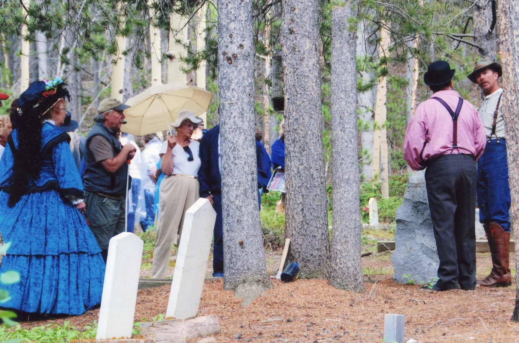 A scanned print of a Cemetery Crawl crowd watching costumed performers among white marble headstones