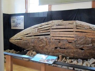 The Mountain Submarine on display in the Gilpin History Museum, a weathered wooden hull on a rock bed
