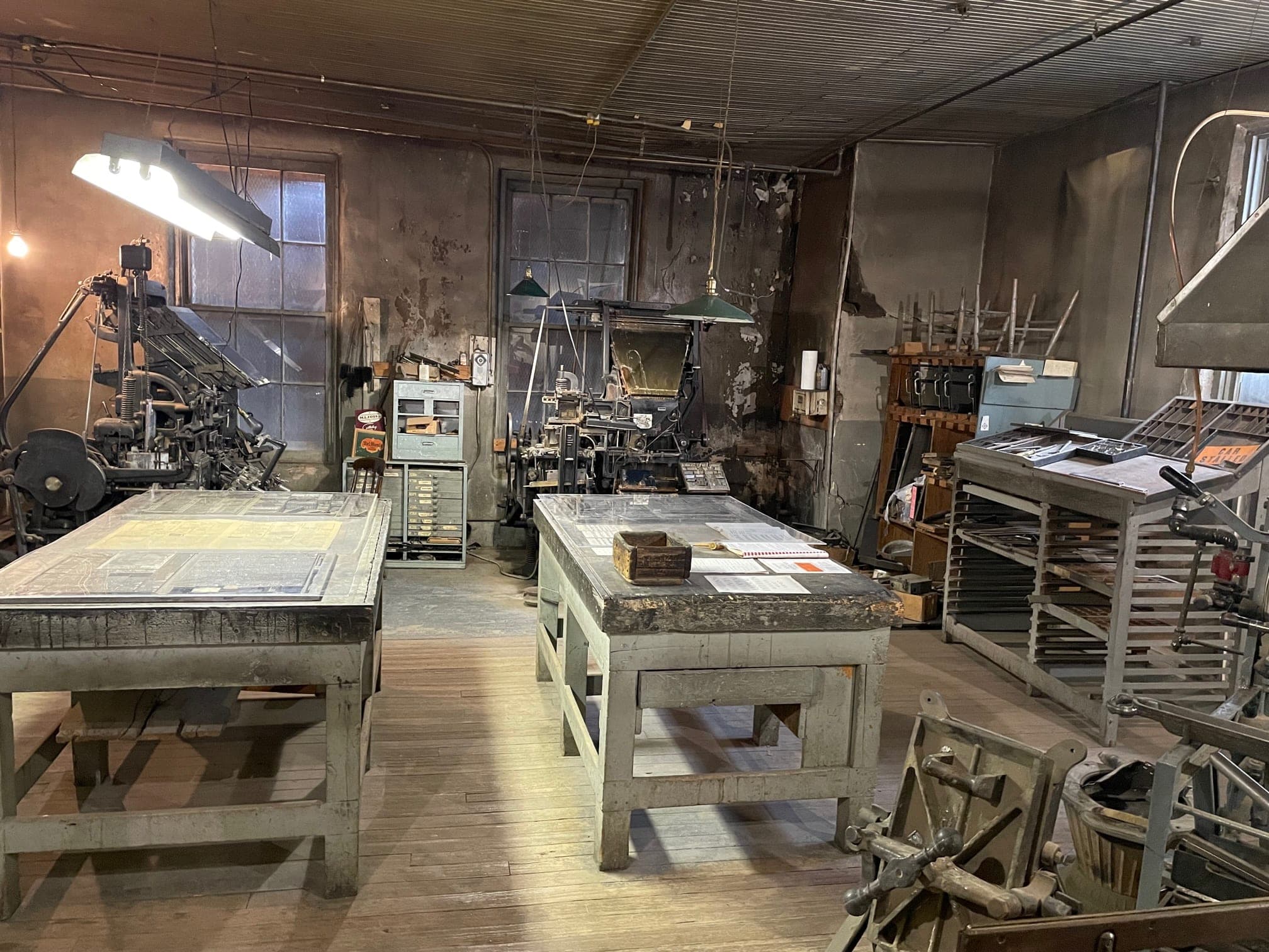 The Weekly Register-Call composing room: Linotype machines, type cases and composing tables under hanging lights