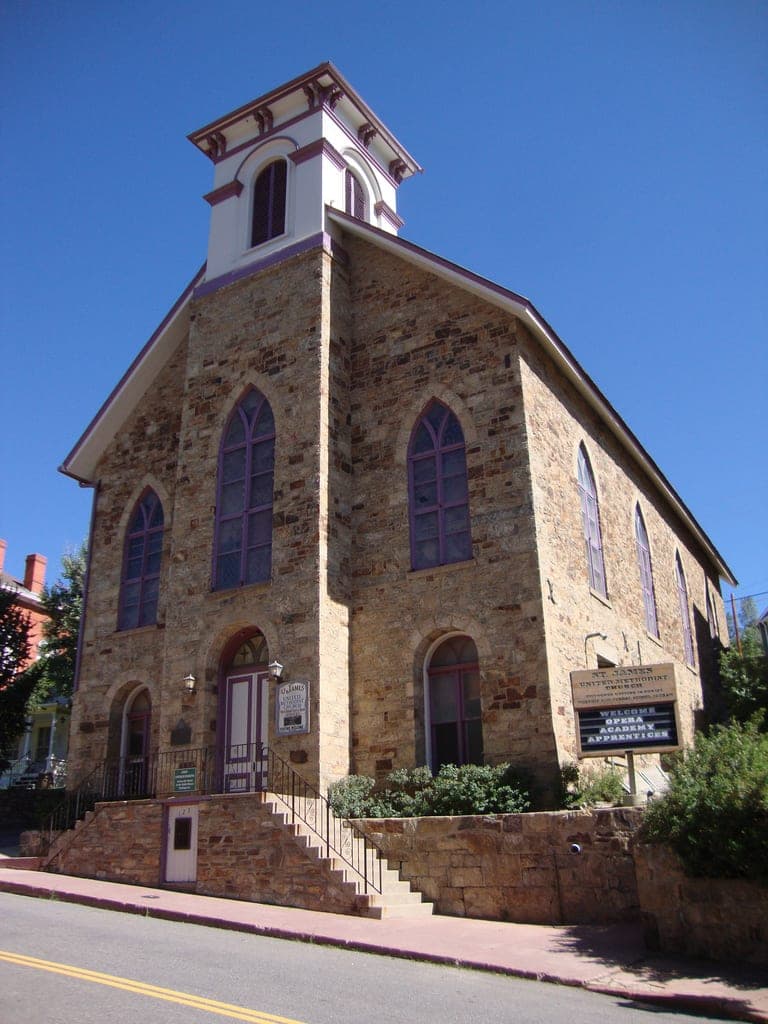 St. James Methodist Church: a stone church with a white bell tower and Gothic windows under a deep blue sky