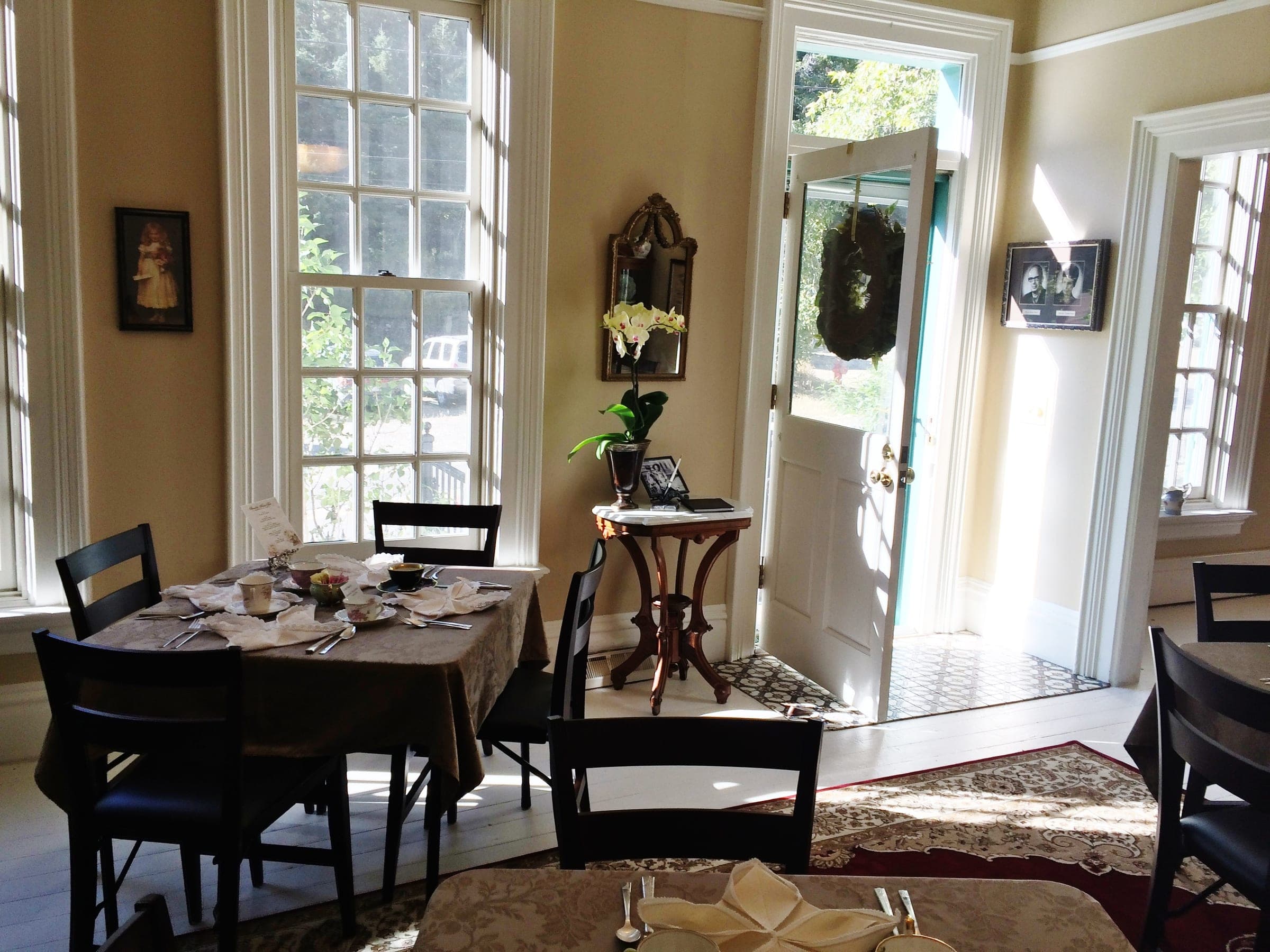 The Stroehle House parlor set for tea, with sunlight through tall windows and the front door open