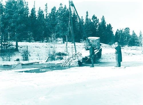 The submarine being hoisted by a crane truck from frozen, snowy Missouri Lake in 1944 as men in coats watch