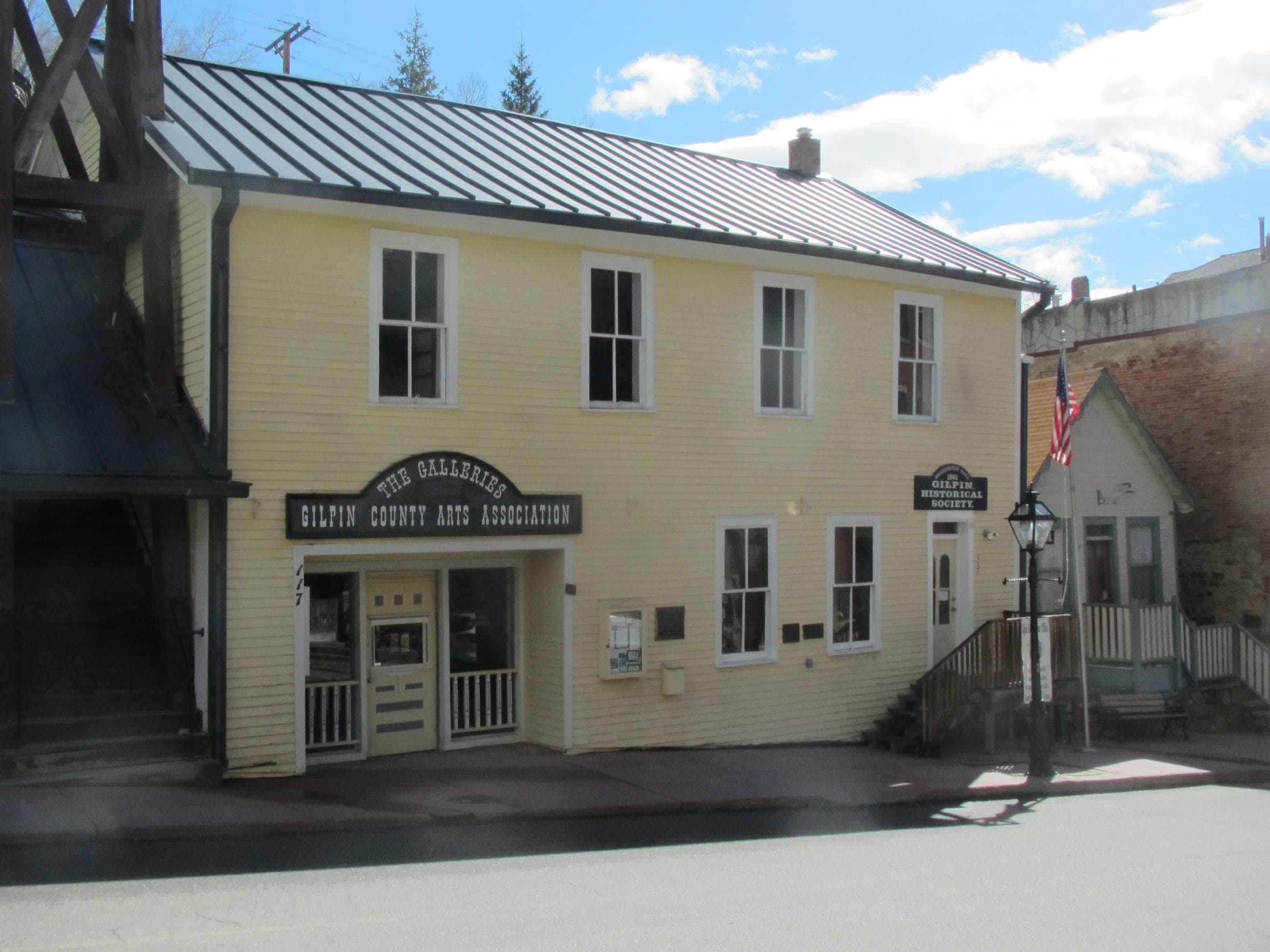 Washington Hall, a pale yellow two-story clapboard building with a flag and a gas lamp